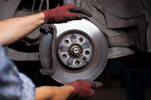 Technician is positioning a new disc brake. Brake noise from your vehicle may mean it is time to invest in a new set of brakes